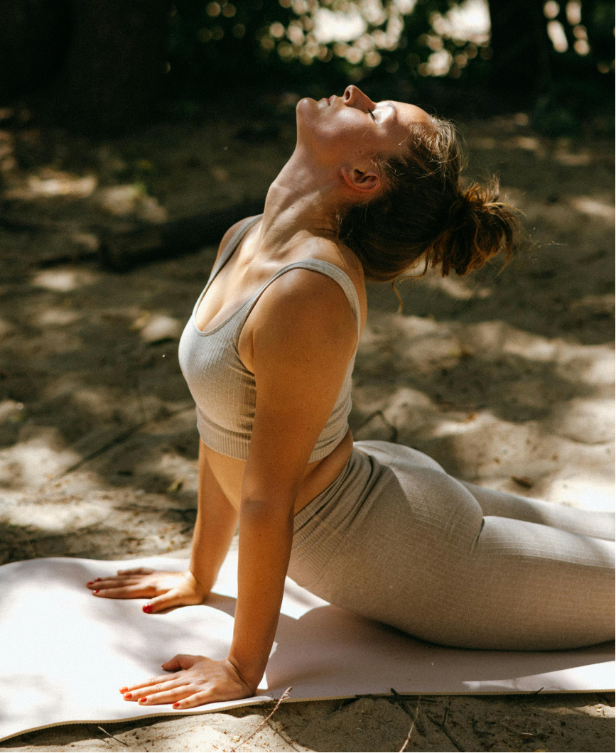 Person practicing yoga outdoors on a mat with trees in the background